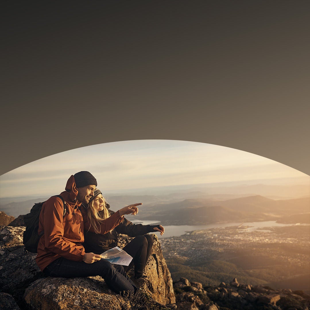 Two people sitting on hillside looking at the view.