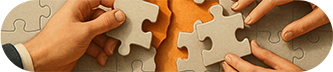 Hands connecting puzzle pieces together, symbolizing teamwork and problem-solving.