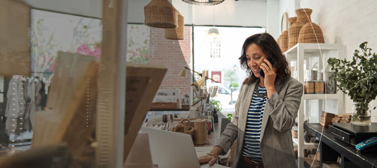 Une femme d’affaires souriante utilisant un ordinateur portable dans une boutique