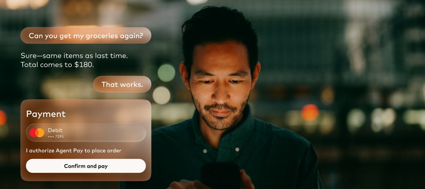 a man looks at his phone with a image of an agentic payment on the screen. 