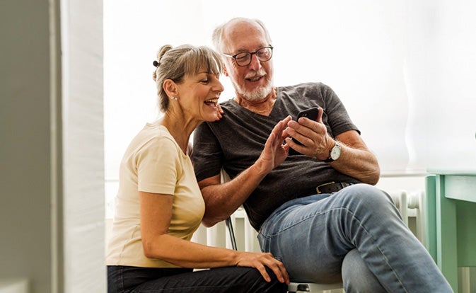 Middle aged couple smiling while looking at a phone.