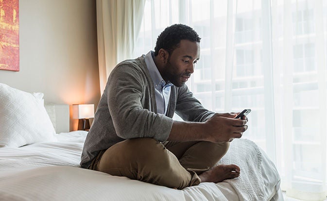 Un homme utilisant son téléphone dans son lit.