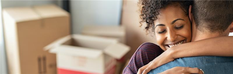 Woman hugging man in front of moving boxes