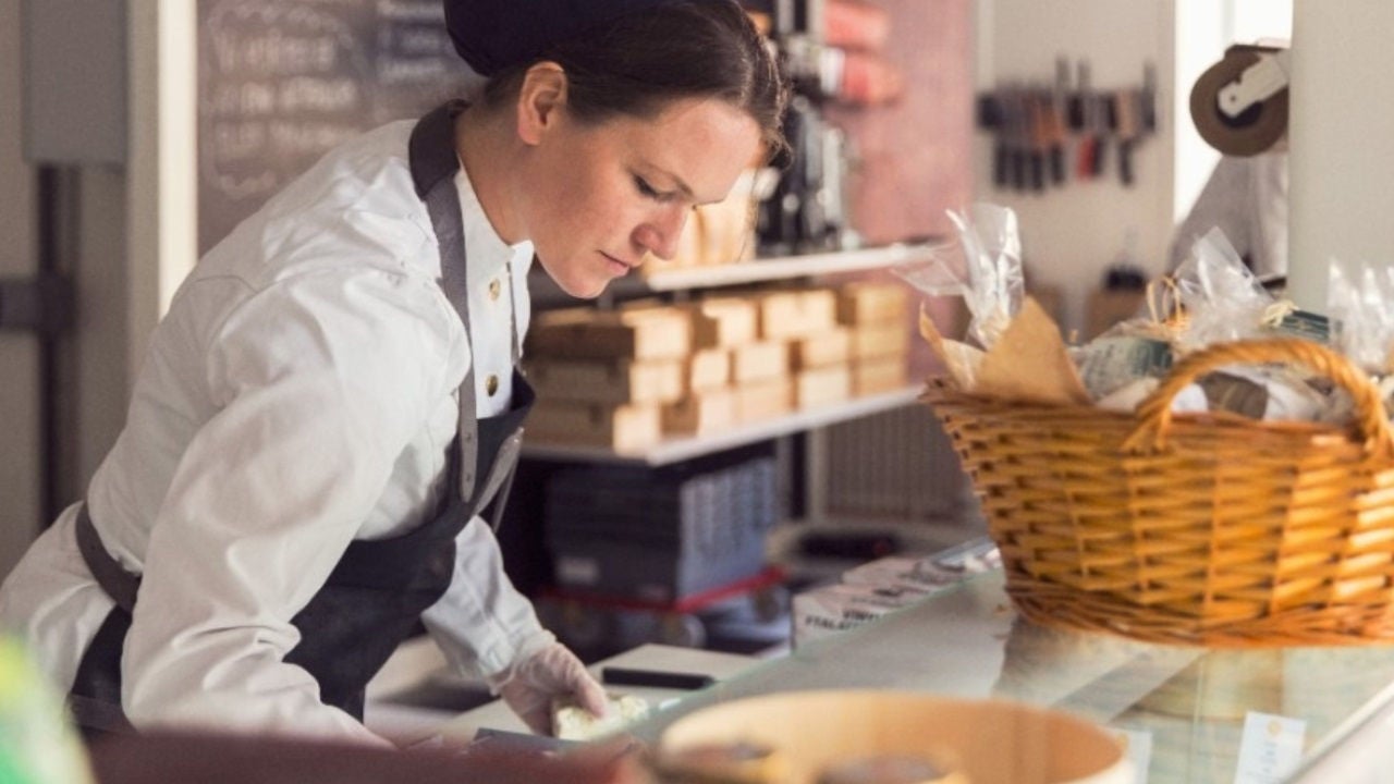 A small business owner in an apron works at a counter. 