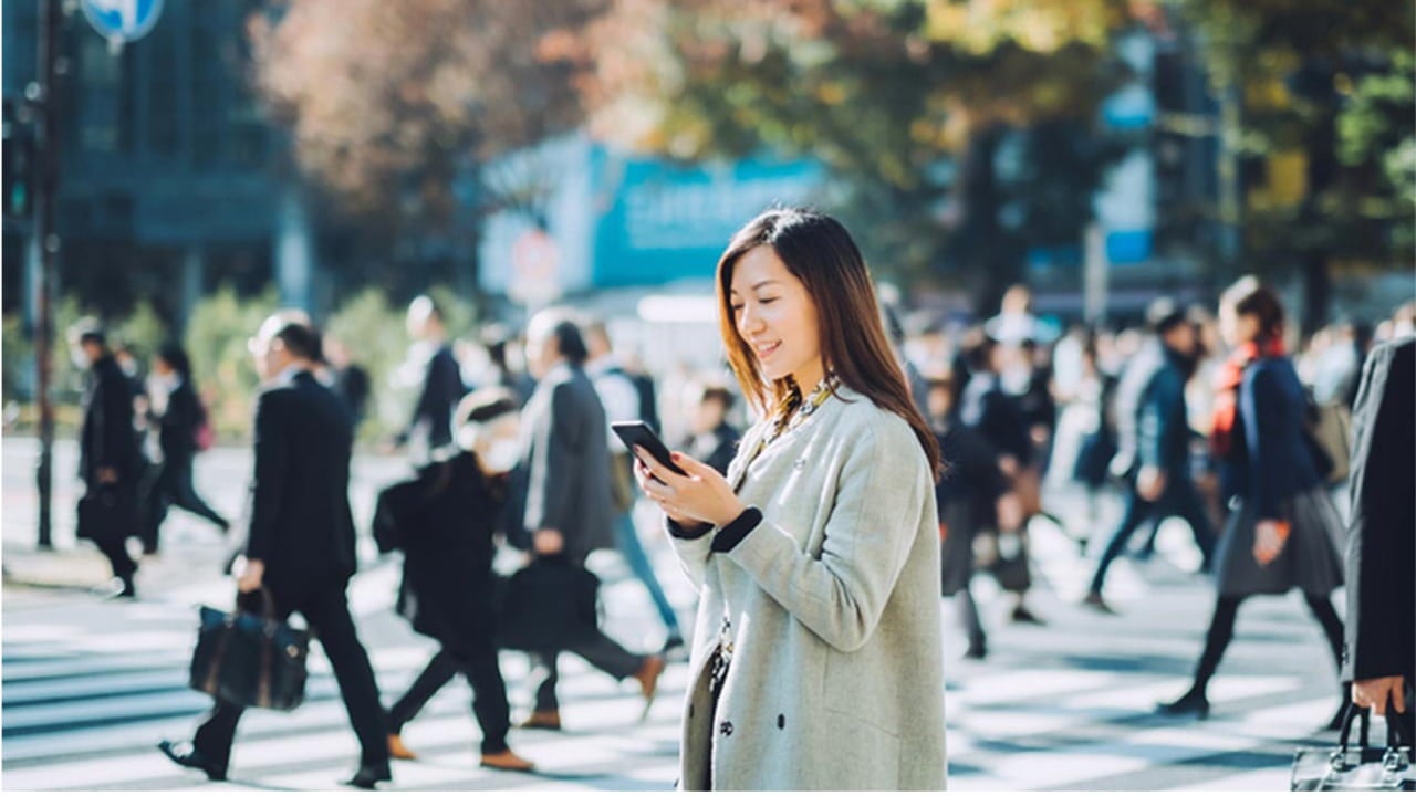 smiling woman using smartphone in a crowded street