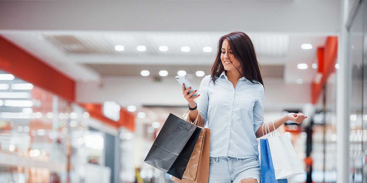 Woman shopping at the mall while using her smartphone