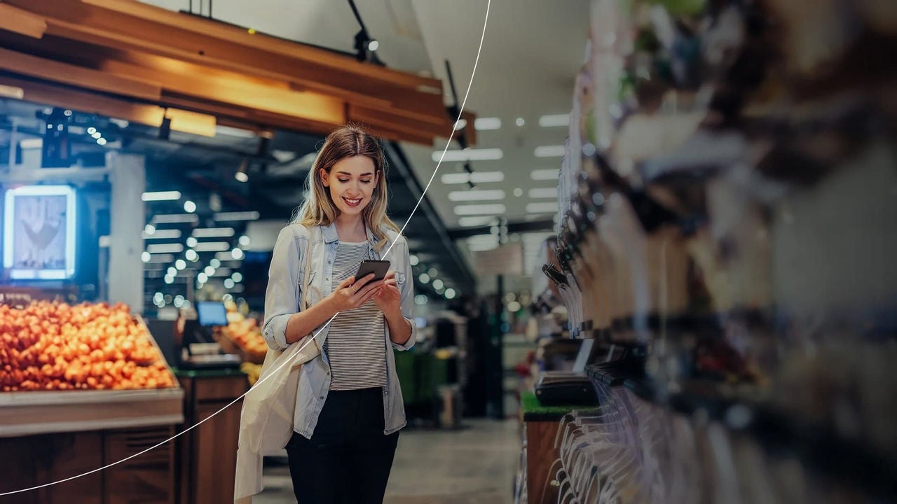 אישה שמסתכלת בטלפון במכולת