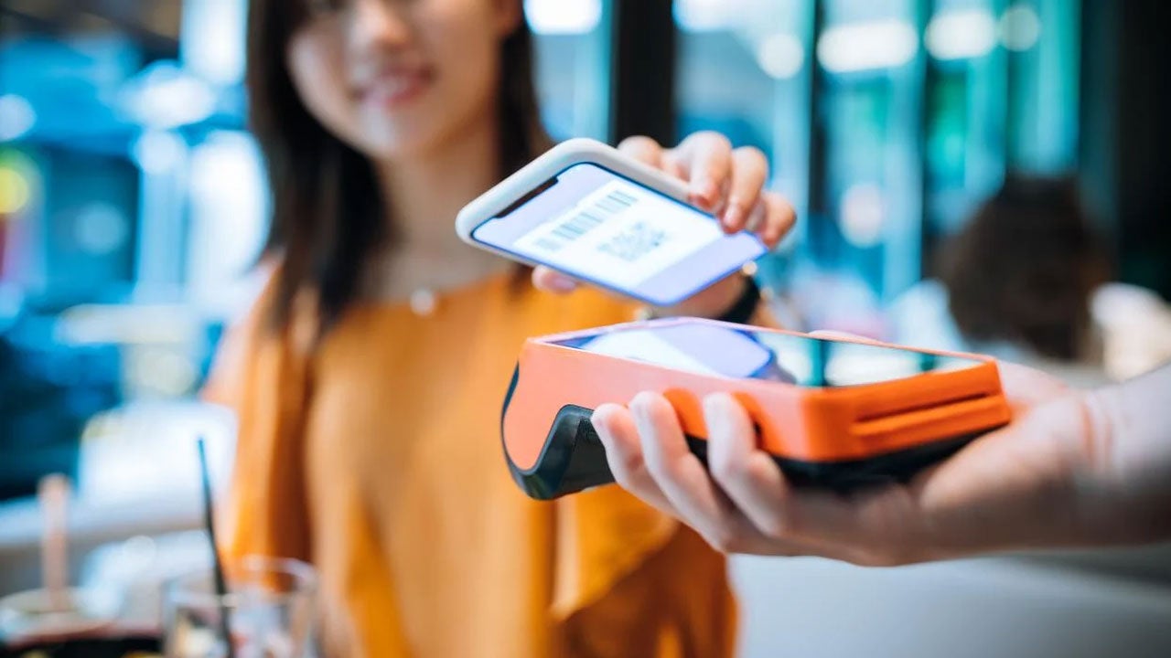 Woman paying with phone at a bar.