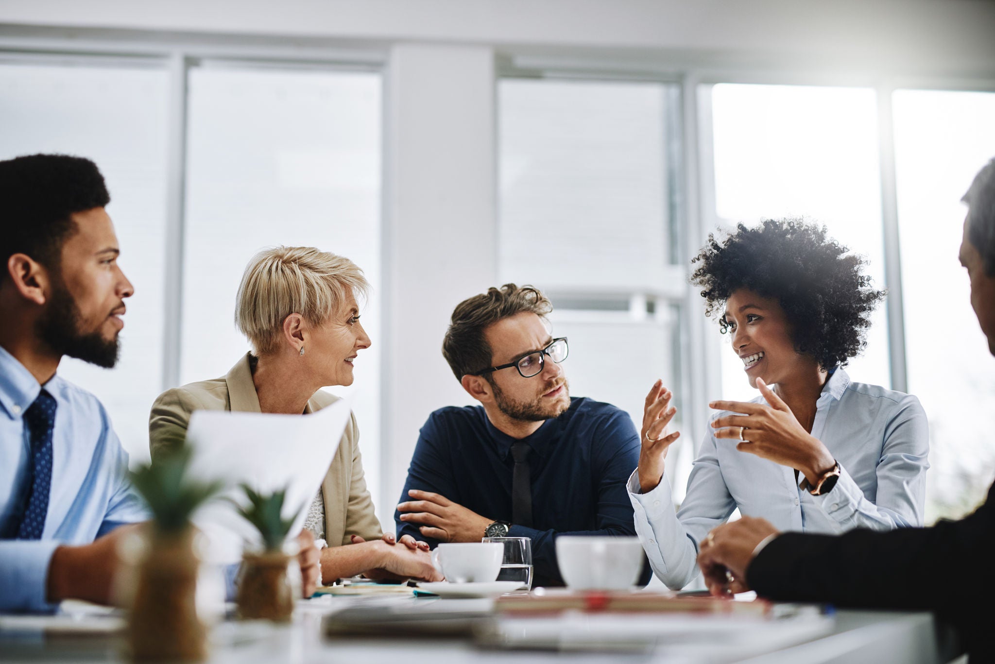 Group of people drinking coffee at a conference table.