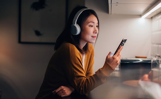 woman wearing headphones and using phone.