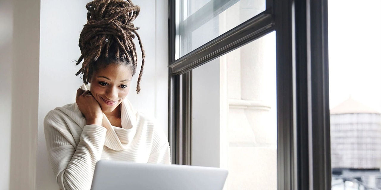 אישה משתמשת במחשב הנייד שלה ליד החלון