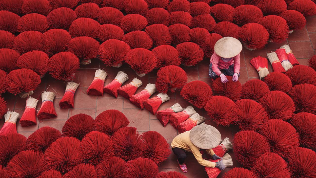 workers drying bright red incense