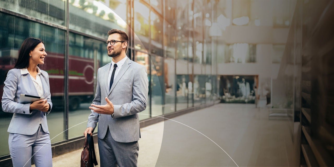 שני אנשי עסקים מנהלים שיחה מחוץ לבניין משרדים מודרני.