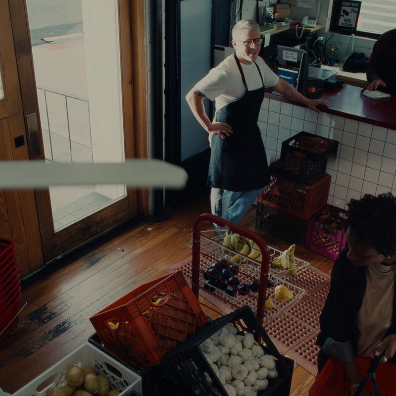 Overhead view of a grocery shop with the owner standing at the counter smiling