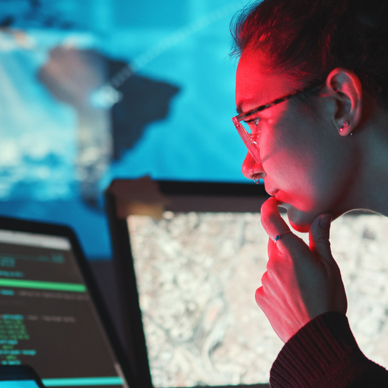A woman looks at a computer screen with a digital map in the background. 