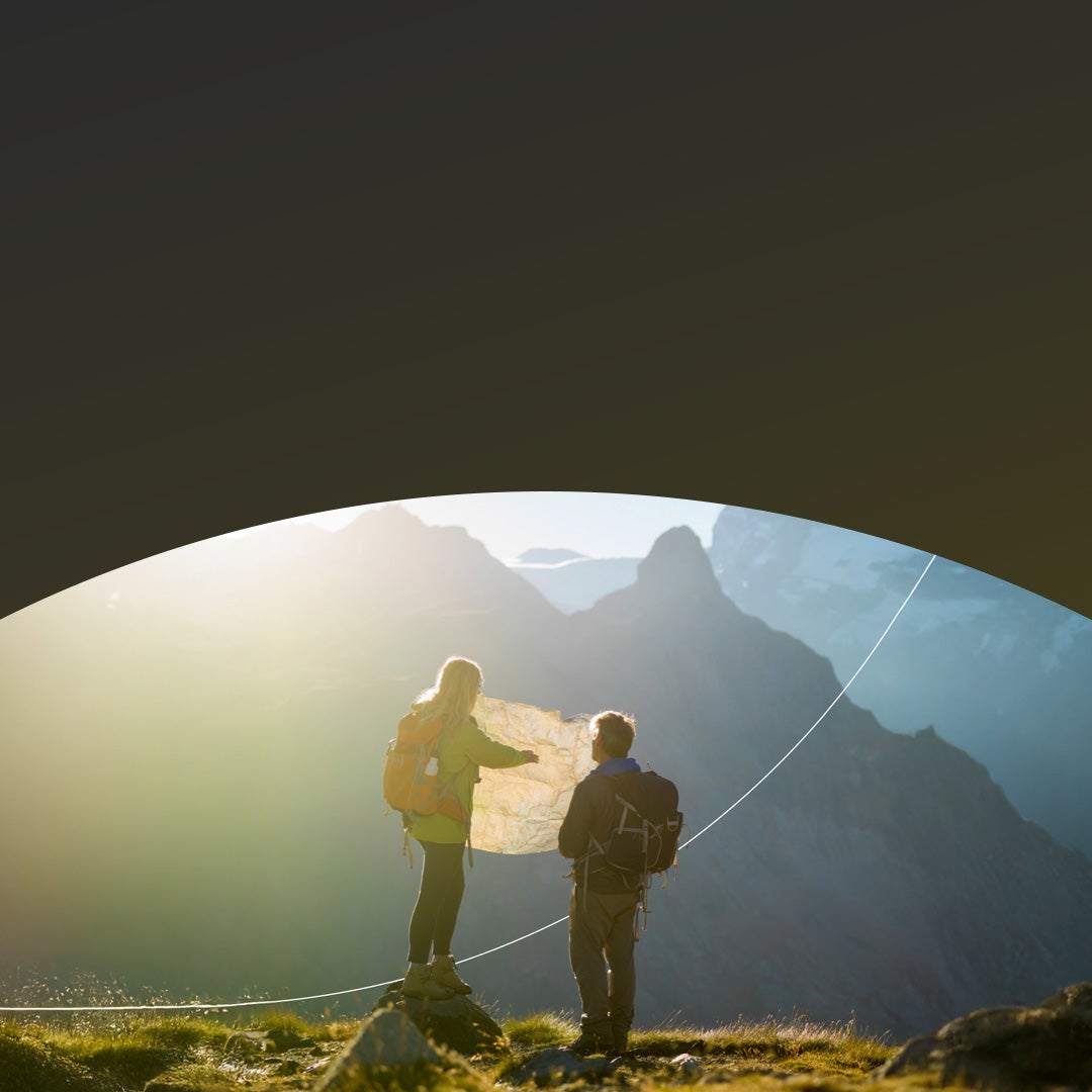 A man and a woman hiking in the mountains looking at a map.
