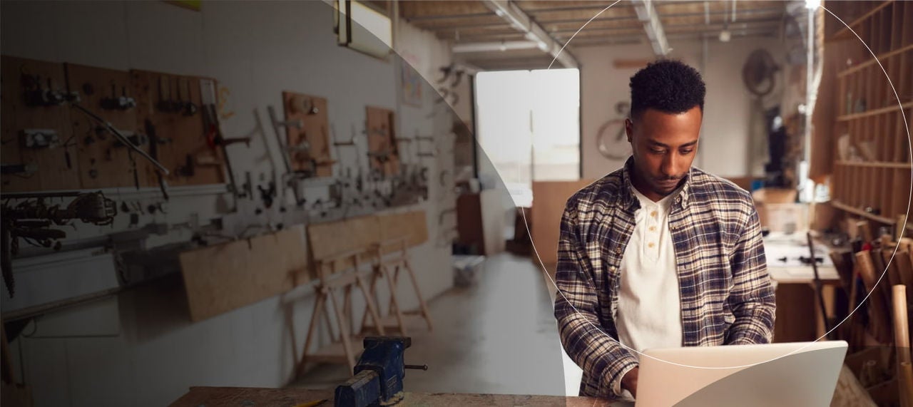Homme en chemise à carreaux utilisant un ordinateur portable dans un atelier