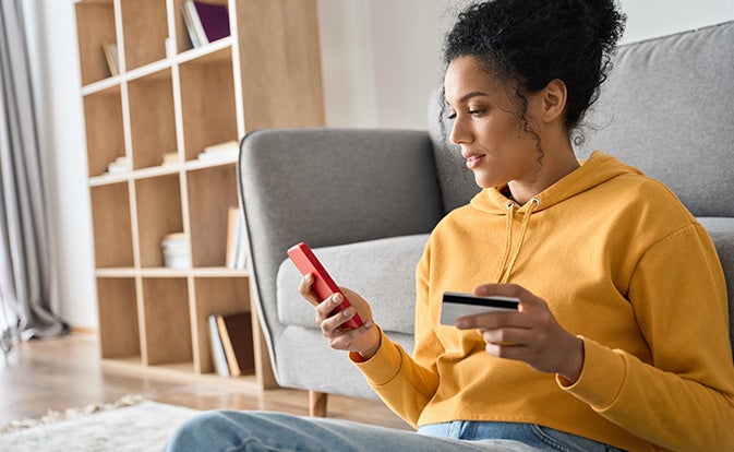 Woman consumer holding credit card and smartphone.