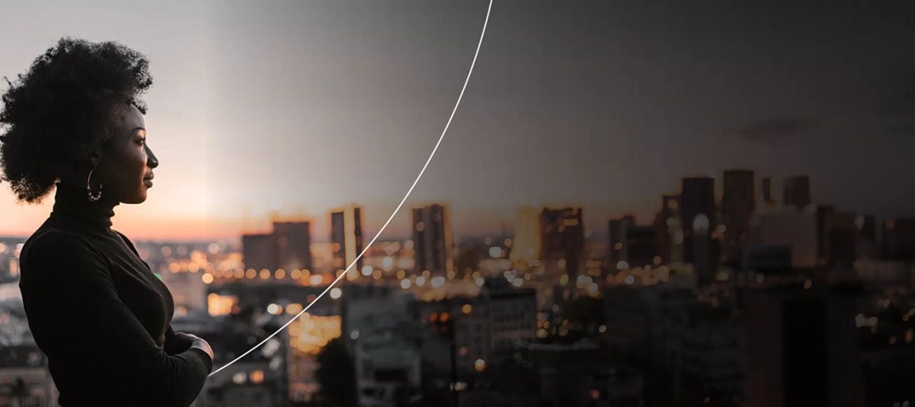 אישה בחוץ על ראש גבעה המשקיפה על העיר בשקיעה