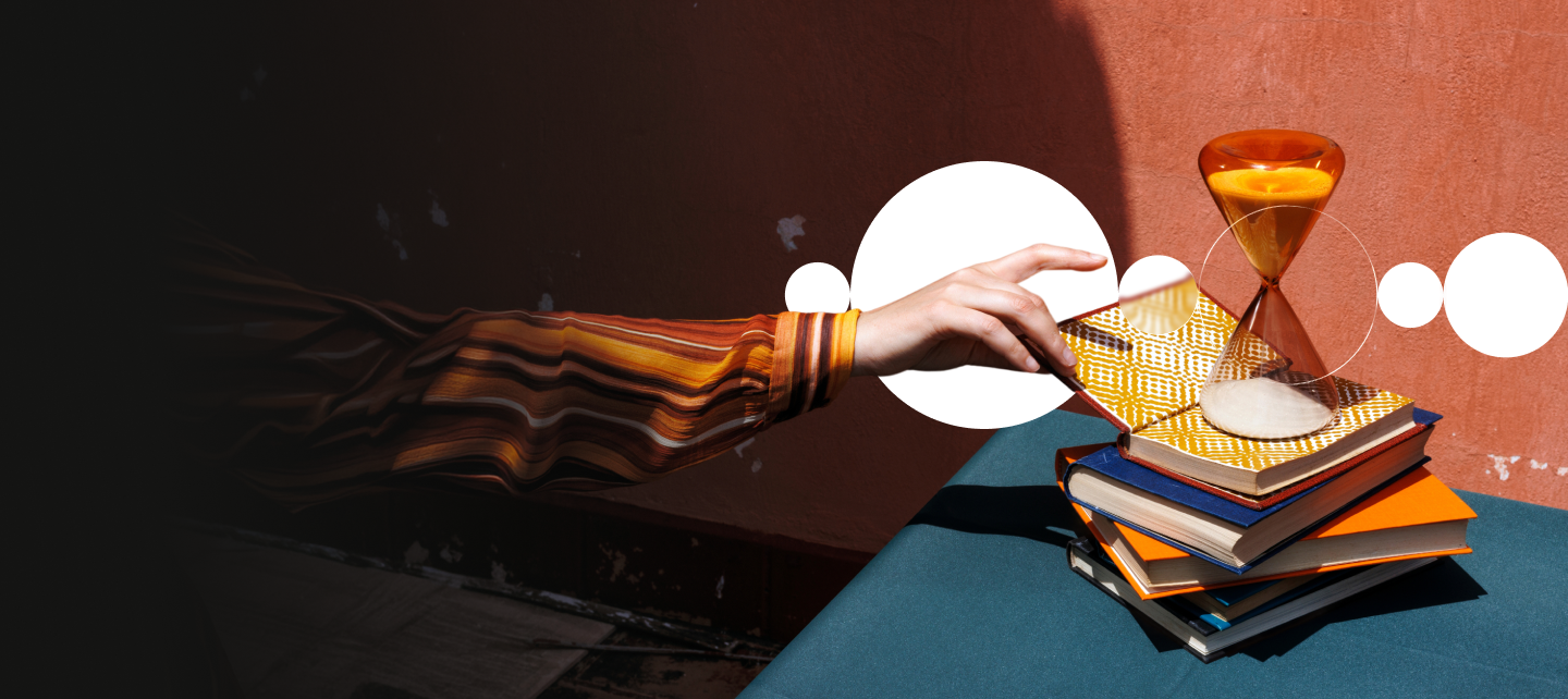 Hand reaching for hourglass and books