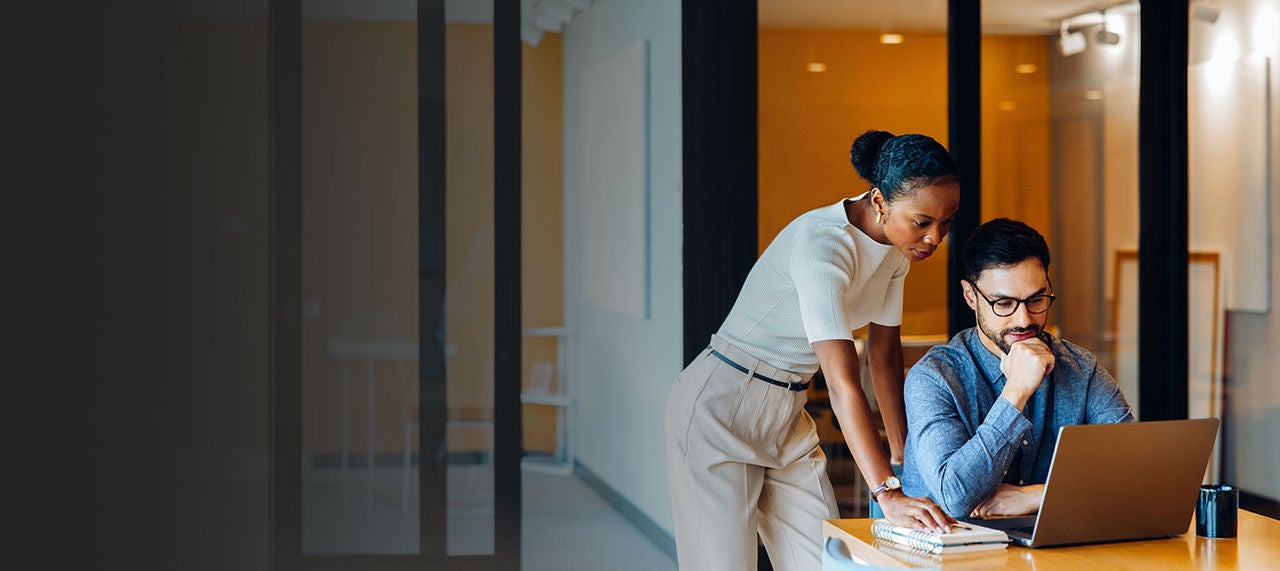 Two colleagues working over laptop in corporate office.