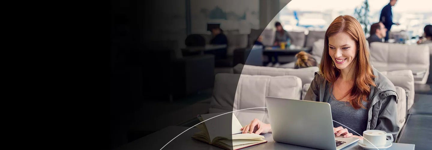 Femme souriant devant un ordinateur à l'aéroport
