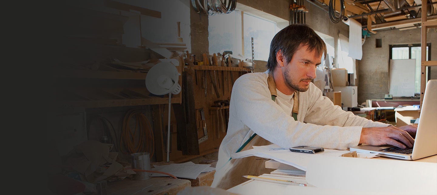 A man working on a laptop in his workshop.