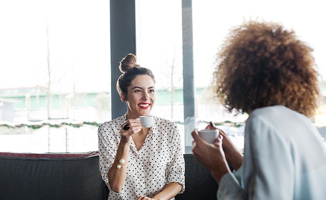 Two people smiling over coffee in a cafe.