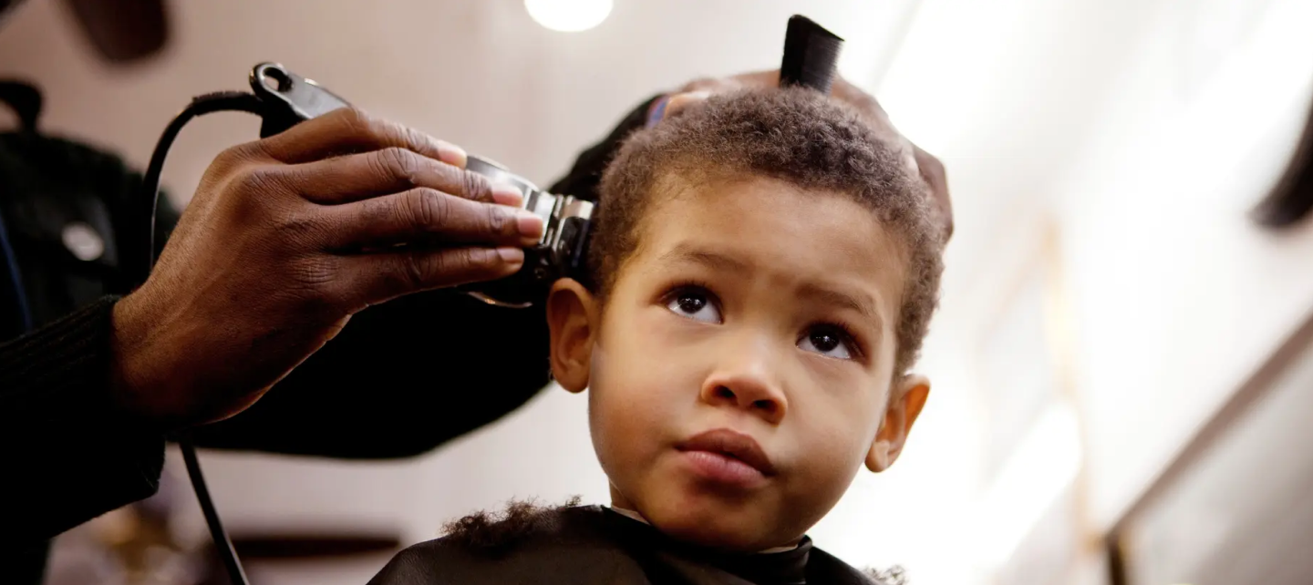 A boy is seating for his haircut