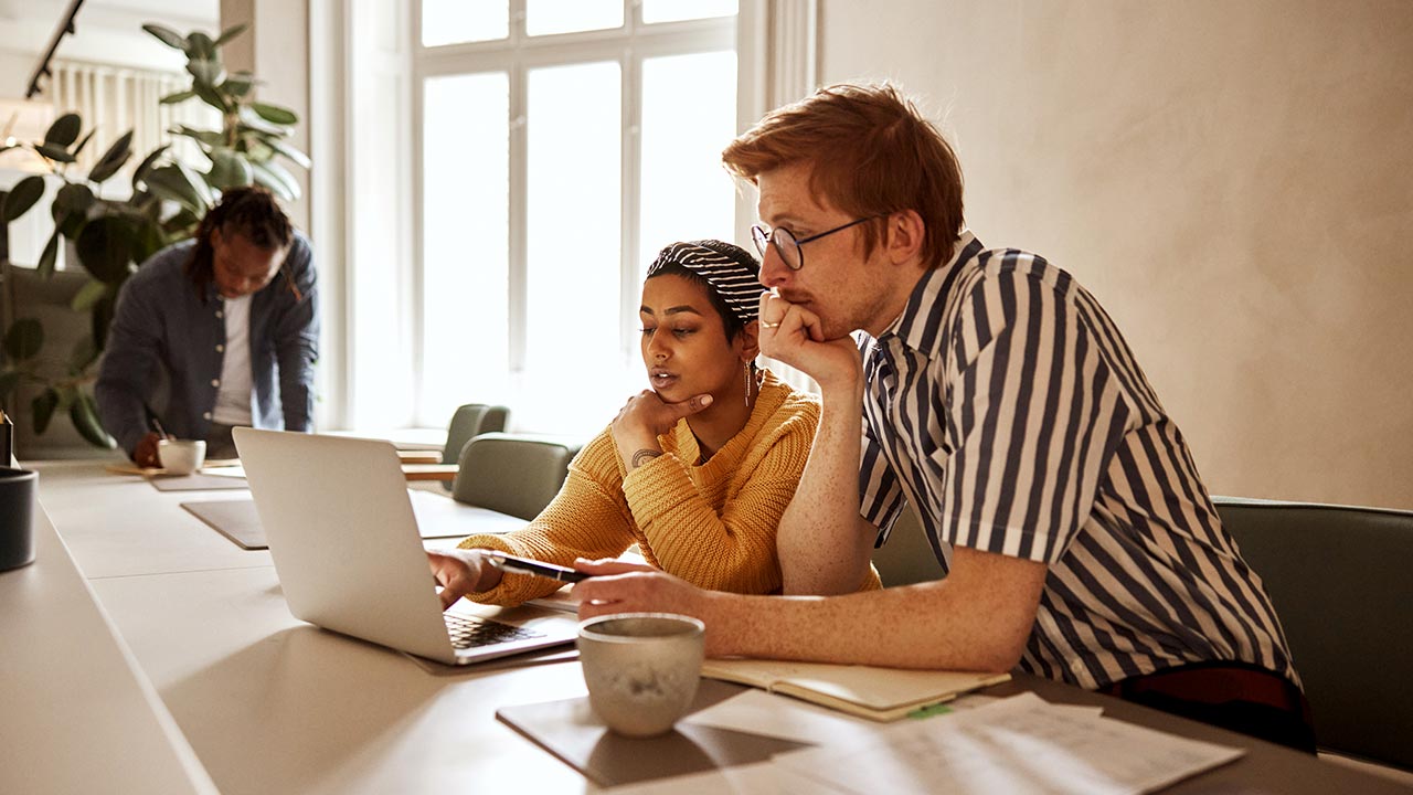 Young colleagues working on laptop together.