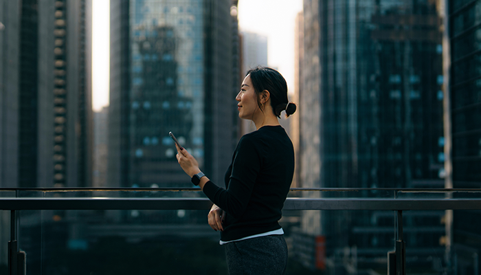 Woman on phone in front of skyscrapers