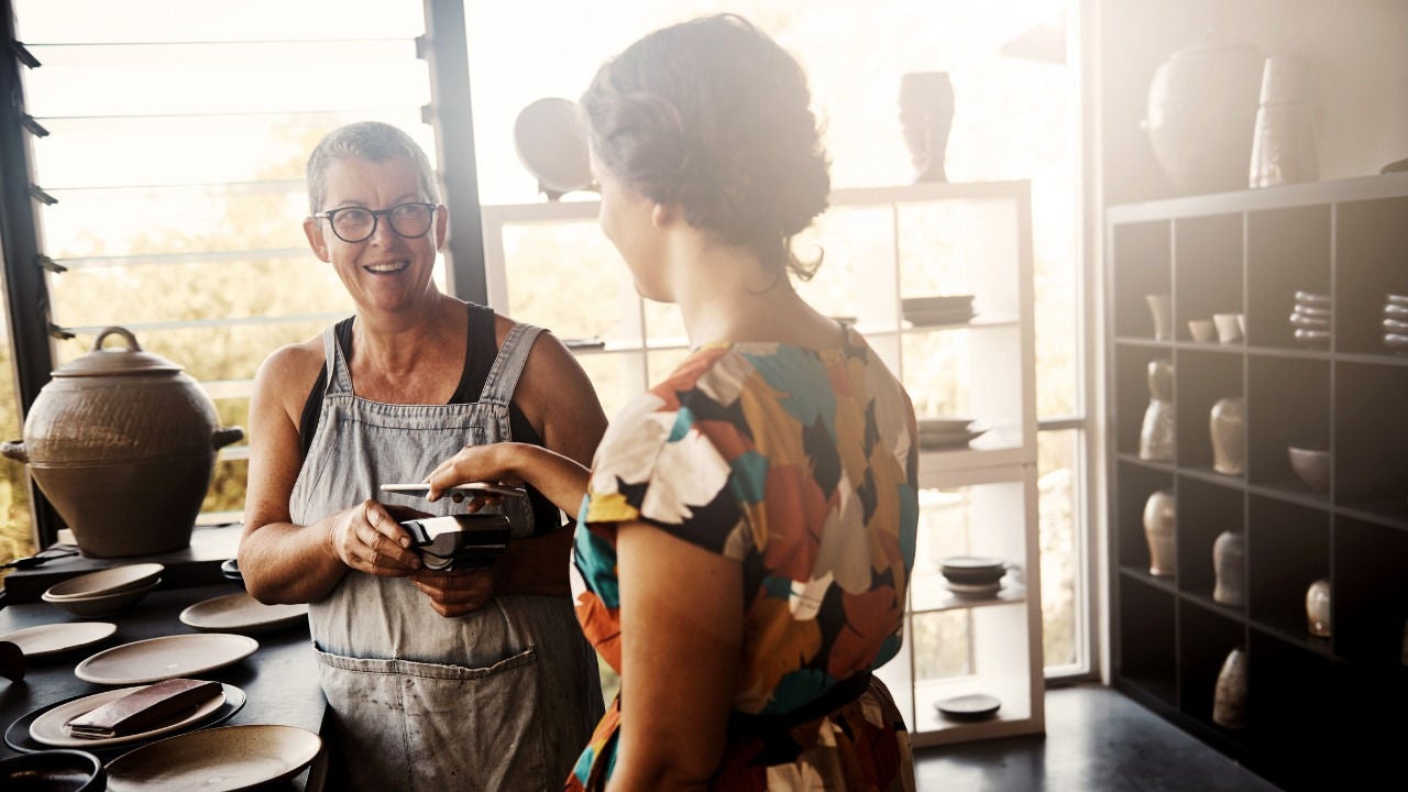 A woman pays for a piece of pottery with her phone. 