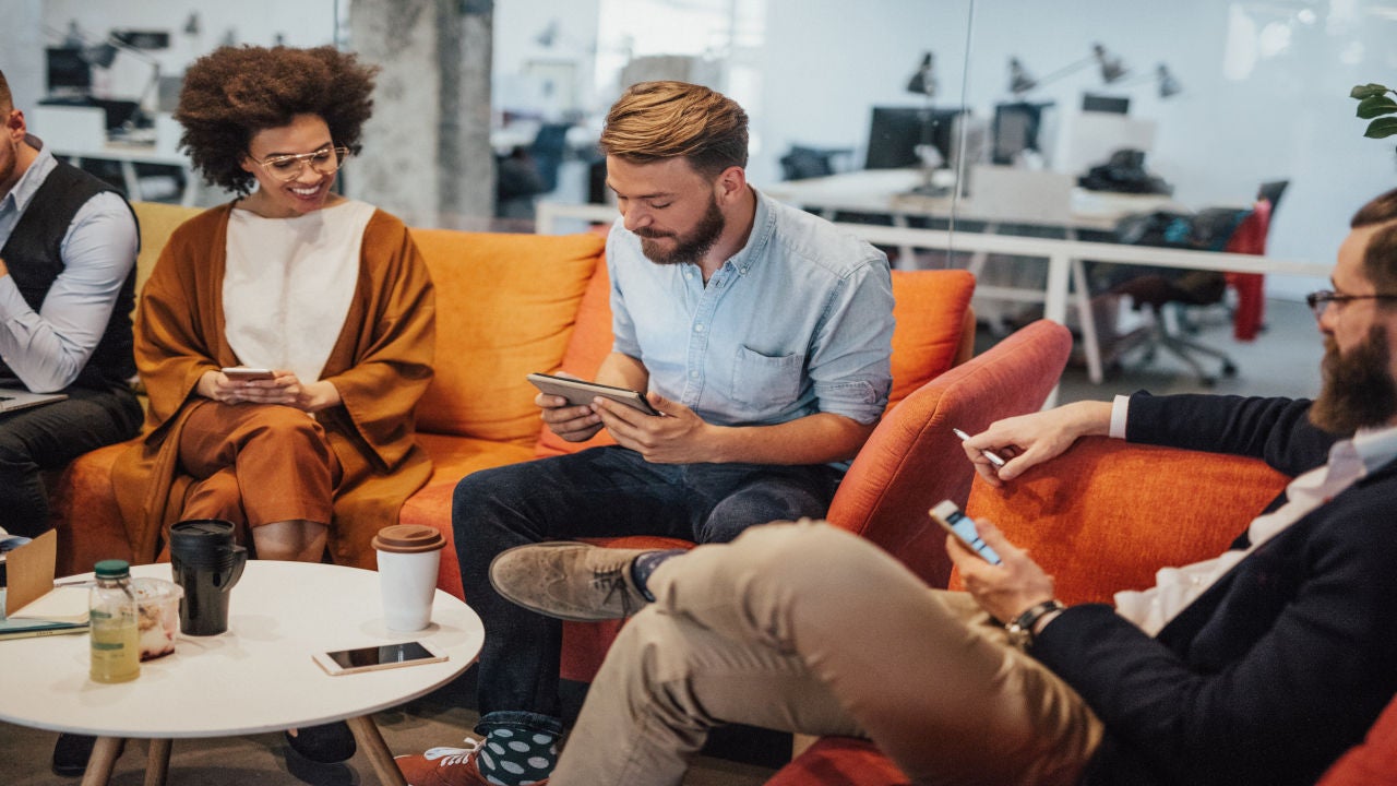 Multi-ethnic group of people chilling at the break room. Business colleagues relaxing on a coffee break. Business people are taking a break together to socialize.