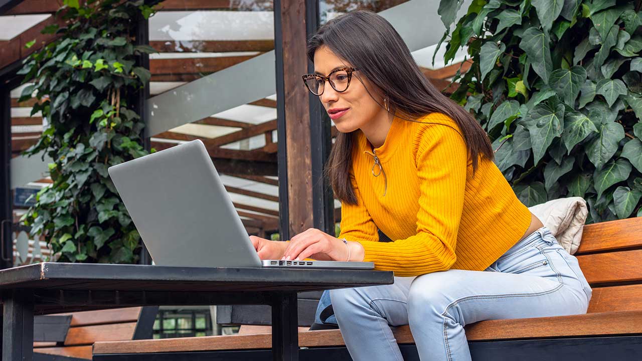 Woman using laptop on an outdoor patio.