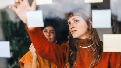 Two women putting up sticky notes