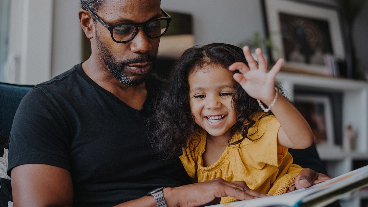 Man holding child while both look at tablet screen.