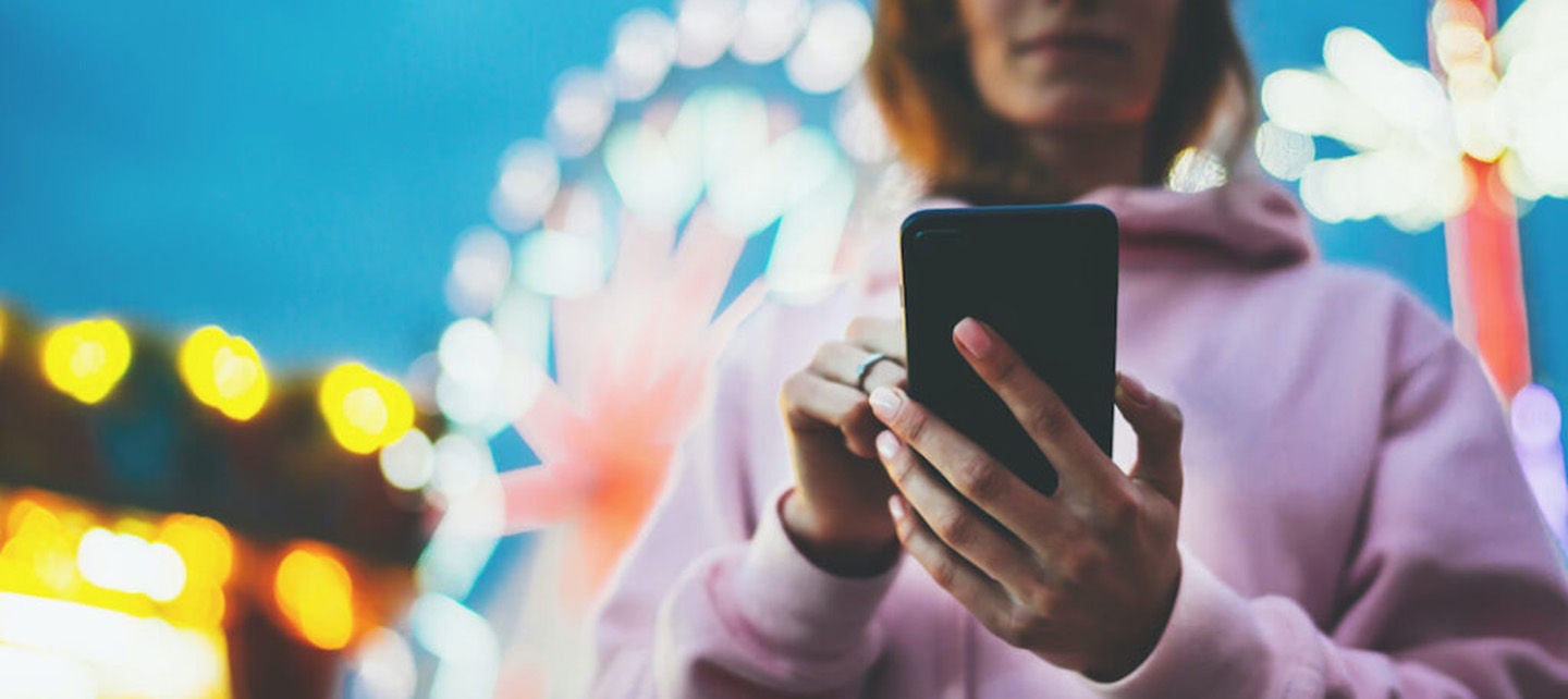 Person am Telefon auf einem Jahrmarkt