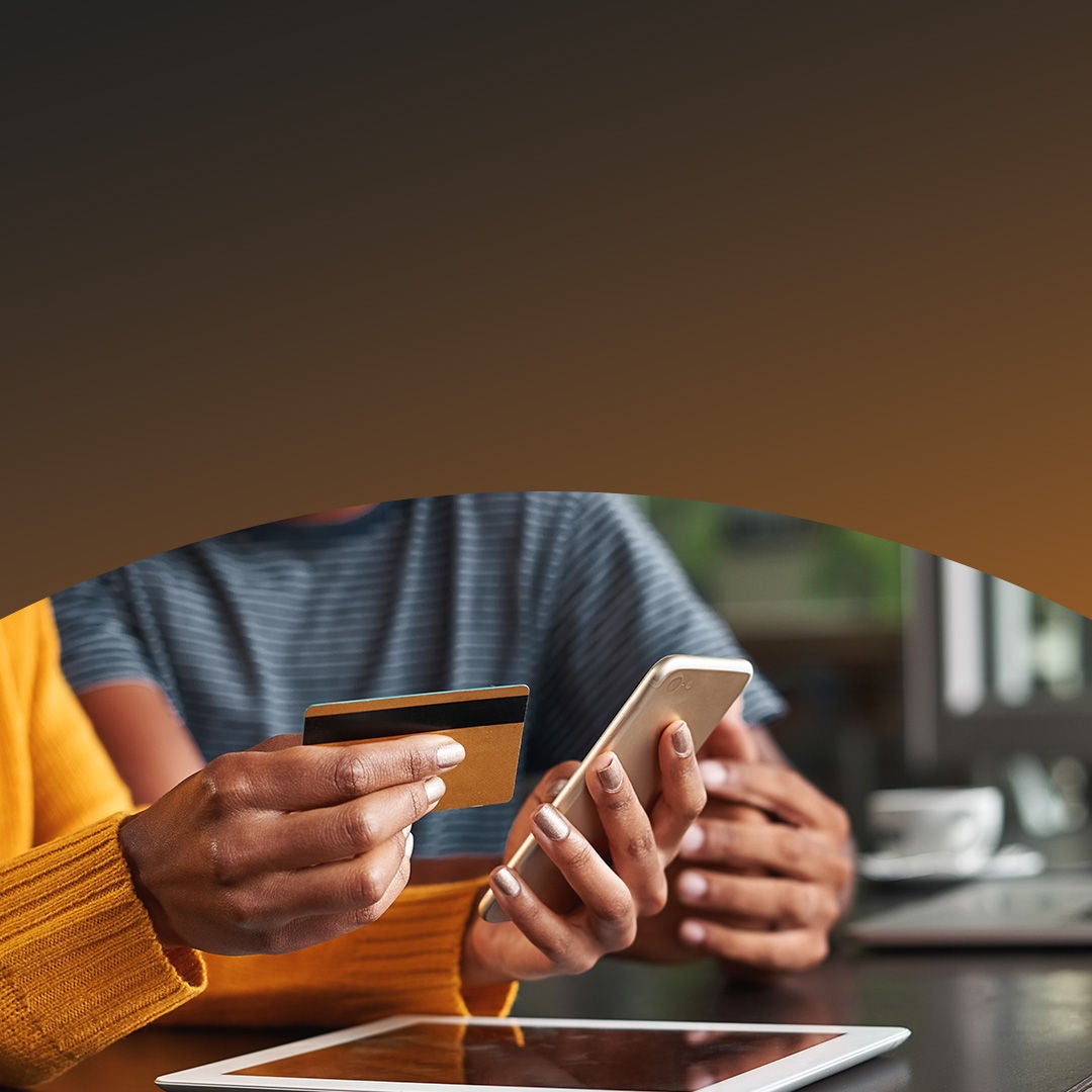 woman holding a credit card and looking at her phone.