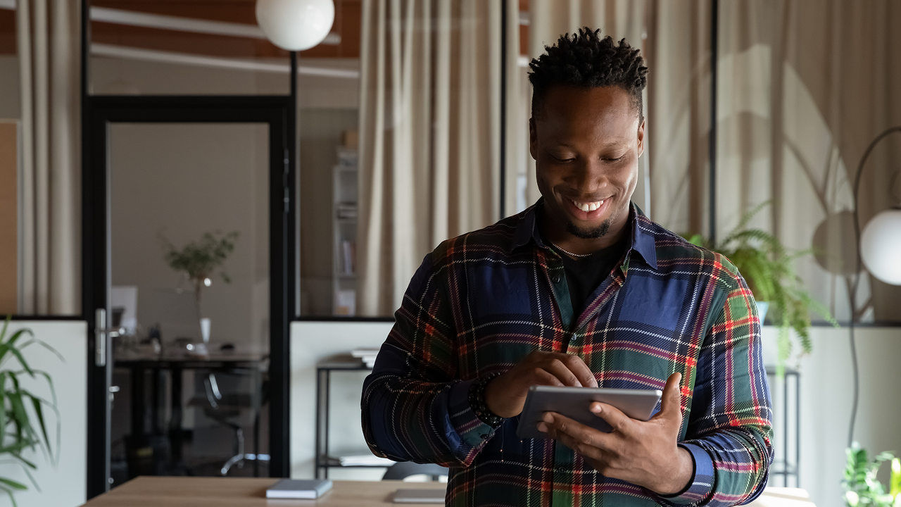 a man standing in a room looking at a tablet