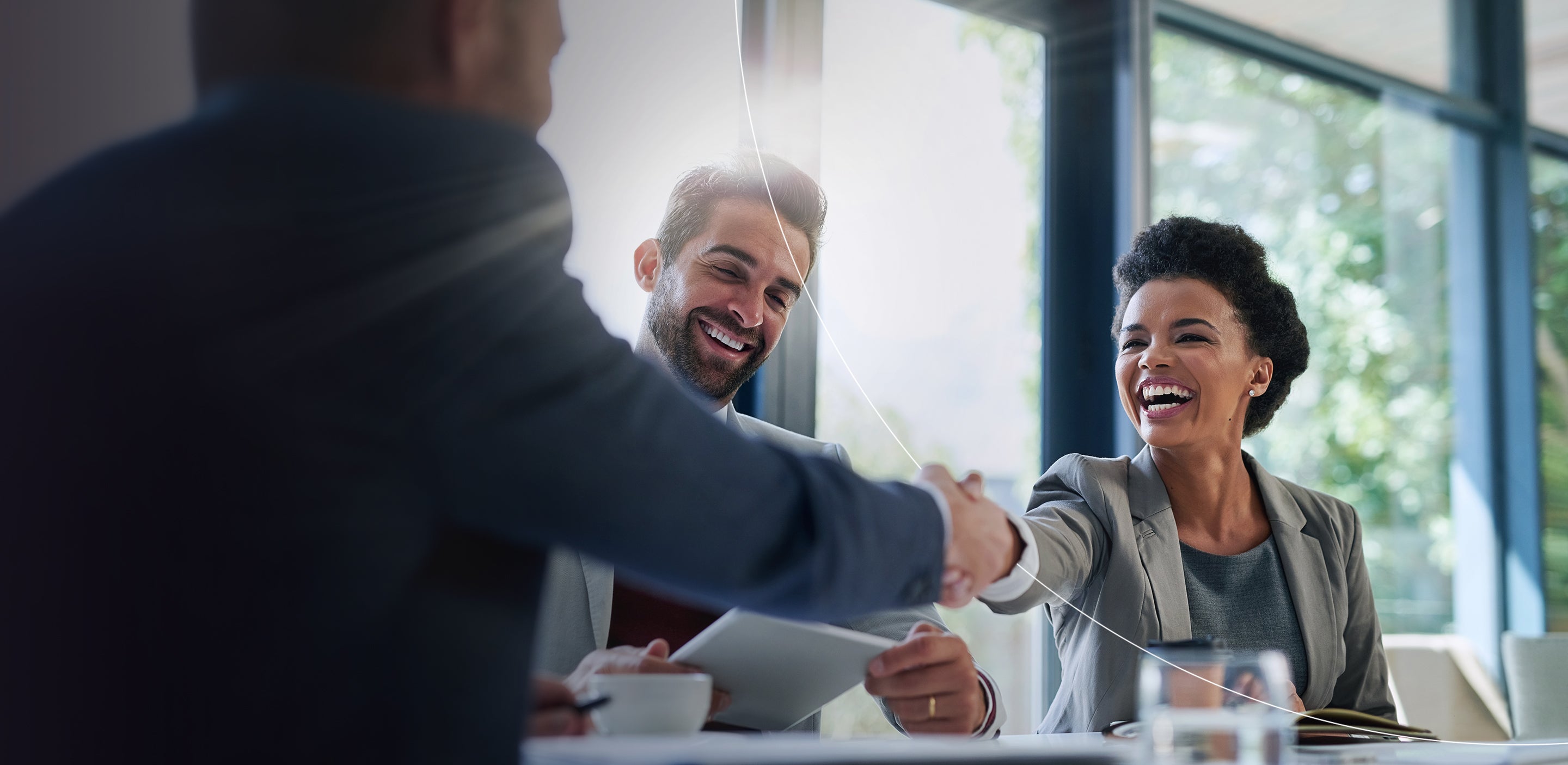 A group of business professionals shaking hands during a meeting symbolizing agreement and collaboration.