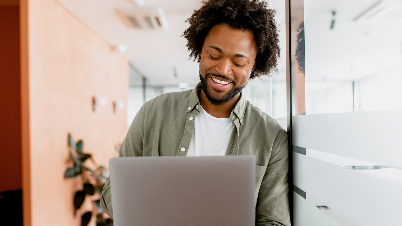 A happy smiling man using his laptop at the office
