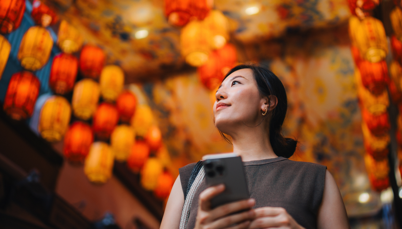 Woman in an asian setting holding her phone looking around
