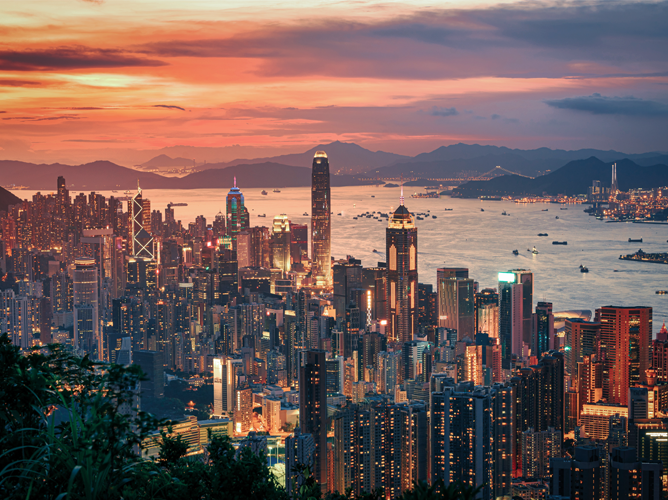 A stunning aerial view of the Hong Kong skyline at sunset, showing the vibrant city lights and its position in the global economy.