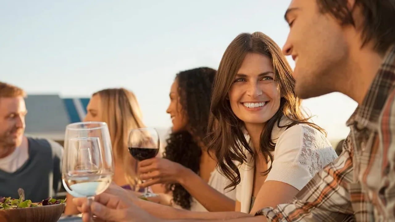 smiling friends drinking wine outdoors