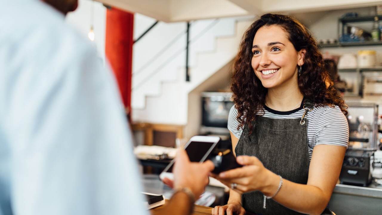 Woman is doing payment via smartphone on cafe counter