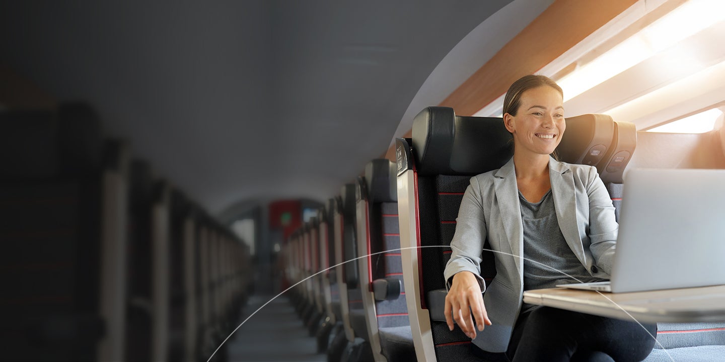 A cheerful businesswoman using her laptop on an airplane.