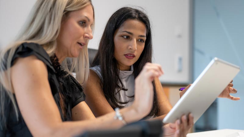 Two businesswomen looking at tablet.