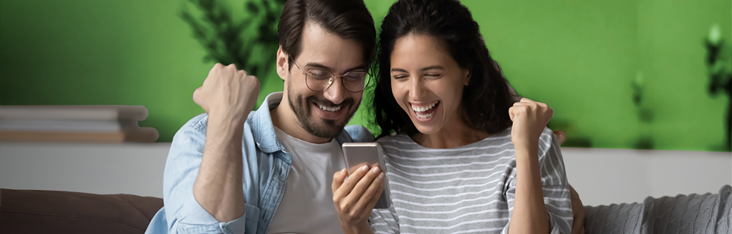 Homem e mulher sorrindo enquanto olham para um telefone.