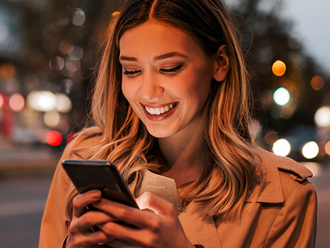 Woman smiling at phone outside