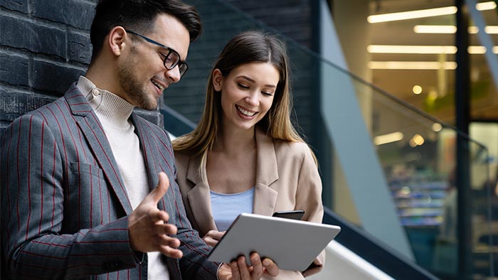 Two collegues looking at tablet outside an office.